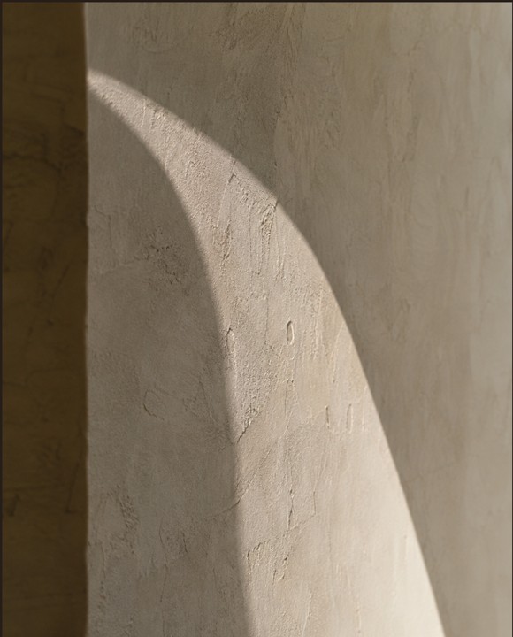 Arc of natural sunlight on a textured mineral wall